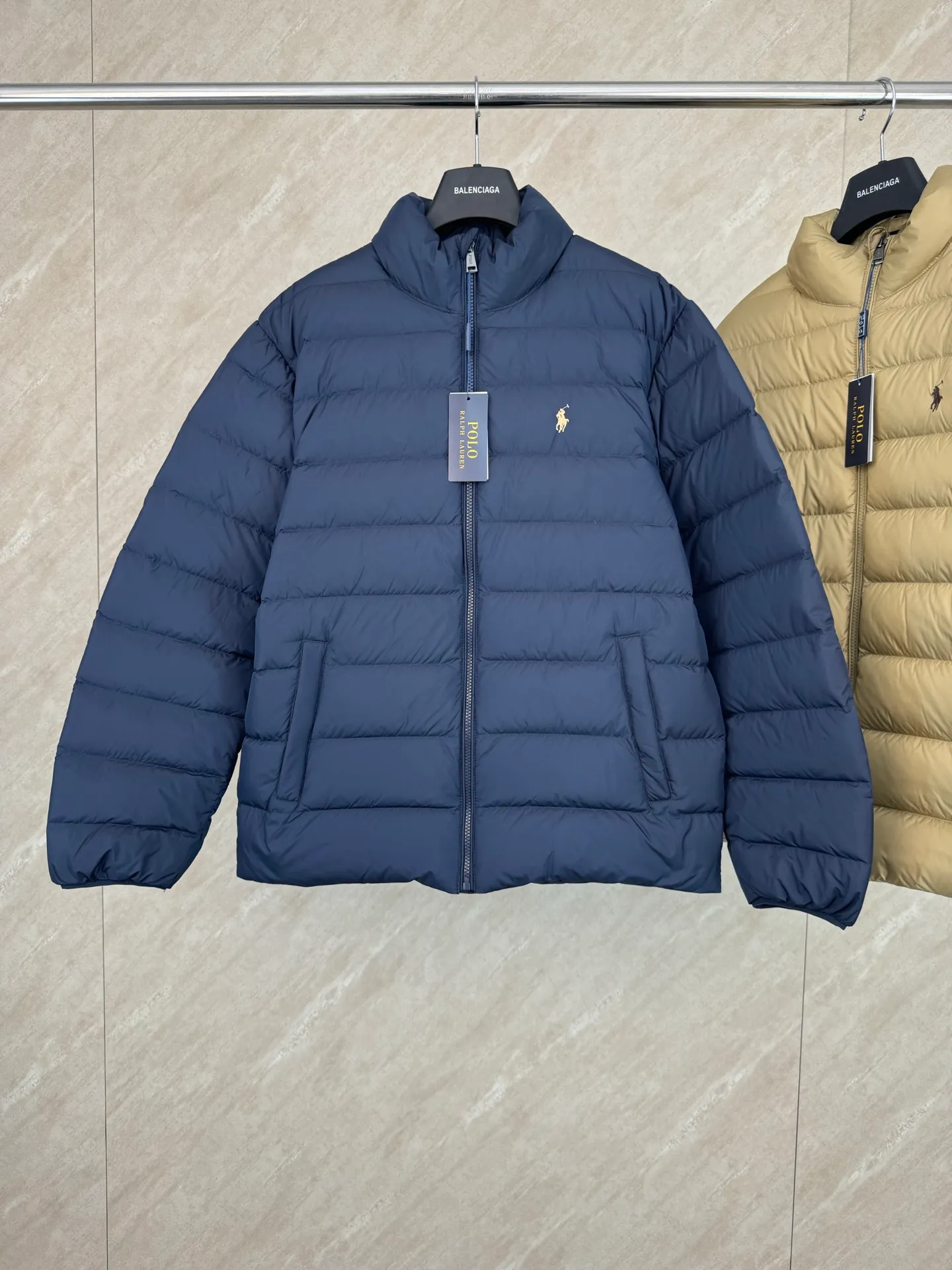 P930 lightweight down jacket size s m l xl Nylon fabric has good windproof and waterproof properties, which can effectively block the intrusion of wind and rain from the outside and keep the inside dry, suitable for wearing in humid or rainy environments.  The red label on the chest is made with an imported MECLO embroidery machine. The original pattern is scanned first, and then high-quality silk thread is used to make a pattern. The density effect is adjusted by continuous pattern making.  Exquisite details: the zipper design is simple and elegant, easy to operate; the closing design of the cuffs and hem effectively prevents the intrusion of cold wind, improving the warmth and comfort of wearing.  High-quality filling: 90 white duck down is selected, with a weight of 260g, ensuring excellent thermal insulation performance. After strict screening and processing, the velvet is not easy to drill, ensuring durability. The hangtags, wash marks, air holes, and four-button buttons are all customized from the original one-to-one mold.